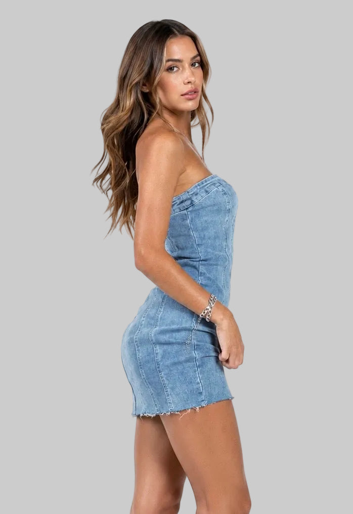 A woman modeling a strapless light-wash denim mini dress with a frayed hem, shown in profile against a plain white background.